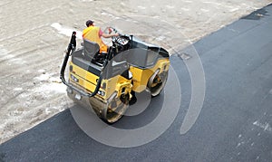 Road roller of an asphalt paving machine at work on freshly laid tarmac.