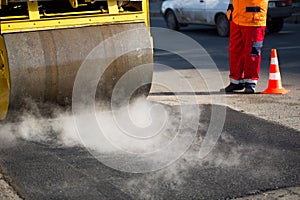 Road roller compacting asphalt during road repairs.