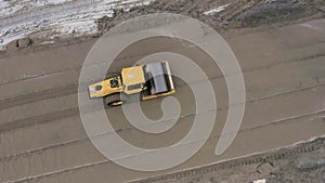 A road roller is driving on a construction site.