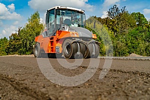 Road roller working on the new road construction site. Laying a new asphalt on the road. Construction of the road