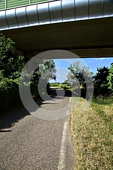 Road in the shade passing under a viaduct in the italian countryside in summer