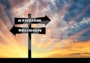 Road sign atheism and religion at sunset