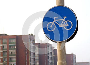 Road sign for bikes lane with urban buildings on background