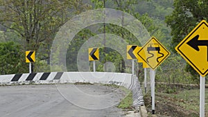 Road sign caution indicating left turn and danger of slippery road on mountain