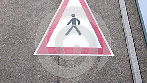 Road sign caution pedestrian crossing with red triangle and walking silhouette on urban street for security and safety in urban tr
