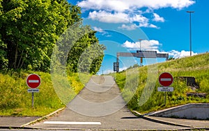 Road sign do not enter. There is no entry to that side. The road goes in the wrong direction. Green trees and blue sky