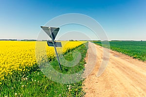 Road sign on the edge of a dirt road in a field