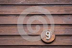 Road sign on a house reading the number nine made out of wood