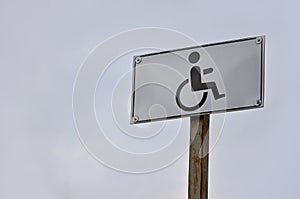 A road sign indicating the crossing of a road for disabled people. White road sign with a picture of a man sitting in a wheelchai