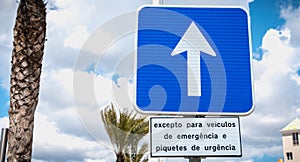 Road sign indicating one way with a sign in Portuguese - except for emergency and intervention vehicles