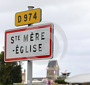 road sign with name of place and the church with bell tower which became symbol of the Normandy landings in France