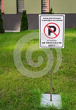 Road sign, No parking sign stands on a freshly mowed lawn. Translation into Ukrainian