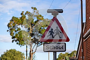a road sign outside a school showing children crossing warnings