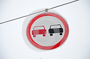 Road sign. Overtaking is prohibited. The sign prohibits overtaking all vehicles on the road section. A red and black car is depict