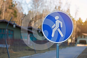 Road sign `Pedestrian zone`. The sign is installed before the beginning of the alley in a country cottage village