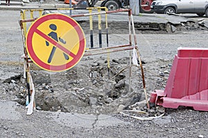 A road sign that prohibits pedestrian traffic.  The pit is fenced.