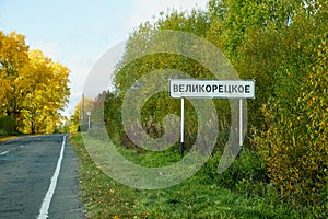 Road sign showing entrance to the city or village in Russia. Russian name of the village Velikoretskoe on the track in foresti