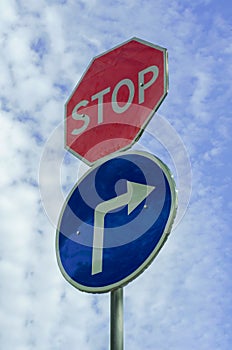 Road sign STOP and movement to the right on the background of the cloudy sky