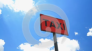 Road sign with TAXI written on an orange background with blue sky