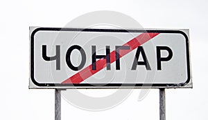 Road sign with text Chongar Chonhar, name of Ukrainian city in Kherson oblast, crossed out