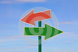 Road sign with two different arrows over blue sky