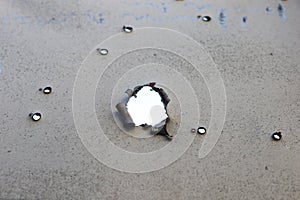 The road sign of the village, in the place of hostilities. Bullet holes in metal