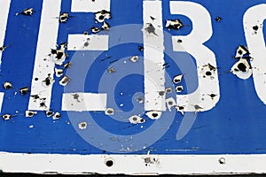 The road sign of the village, in the place of hostilities. Bullet holes in metal