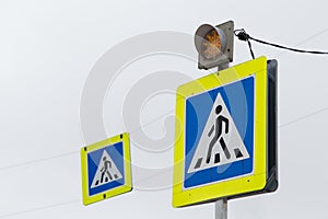 Road sign white triangle with a man in a blue square means a pedestrian crossing