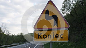 Road sign winding road and the inscription in Polish - the end