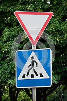 Road signs on a background of trees, give way, pedestrian crossing, traffic rules, road markings