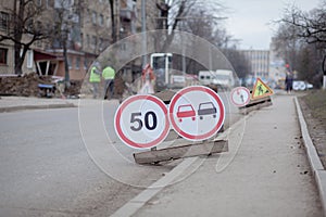 Road signs, detour, road repair on street background, truck and excavator digging hole