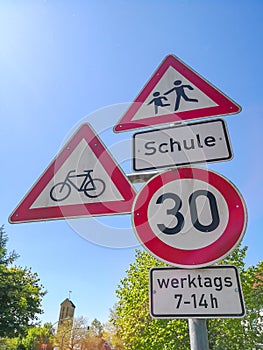 Road signs in front of school speed limit with german text means: school. on weekdays 7-14h