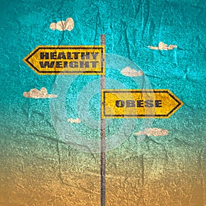 Road signs with healthy weight and obese text pointing in opposite directions.