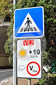 Road signs in Portuguese island Madeira. Blue zebra crossing sign. White speed limit sign. The speed restriction is dependent on