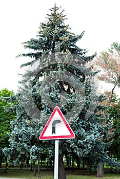 Road signs, road sign dangerous turn to the right on the background of trees