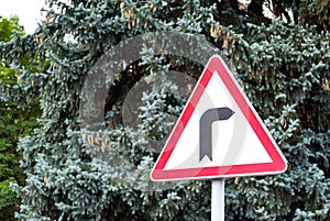 Road signs, road sign dangerous turn to the right on the background of trees