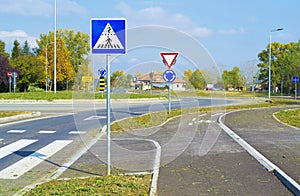 Road signs that shows crosswalk and cycle path ahead of roundabout