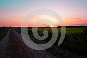 A road during spring time. Summer landscape, sunset with green grass, road and clouds