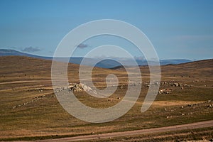 Road in steppe among stones hills and mountains covered with green yellow grass. Baikal nature. Mountain ranges