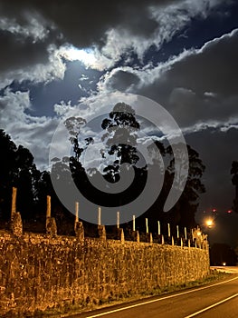 Road and a stone wall during the full moon cloudy night near Eiras, O Rosal, Galicia, Spain, January 2023 photo