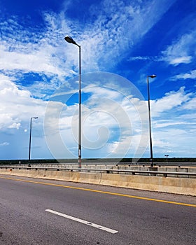 Road and street lights on bridge against sky