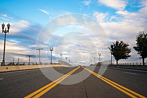 Road with street lights and dividing strip receding cloudy horizon