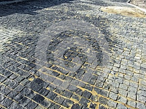 The road on the street paved with gray granite cobbles