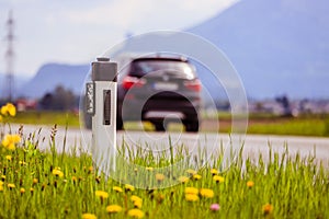 Road in the summer: reflector post, cars, flowers and green grass