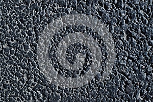 Road texture. Close-up of a dark asphalt road outdoors, top view. Rough granular surface background