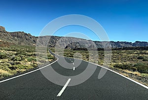 Road though scrubland leading to mountains photo