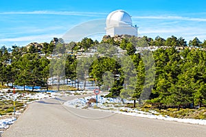 Road to Calar Alto Observatory at the snowy mountain top in Almeria, Andalusia, Spain, 2019. Sky passing through against the domes