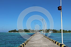 the road to an island from the harbor with a clear blue sky background in ambo island photo