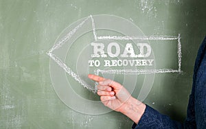 Road To Recovery. Direction arrow on a green chalk board