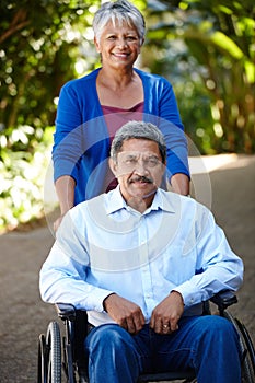 On the road to recovery. Portrait of a senior woman pushing her husband in a wheelchair outdoors.